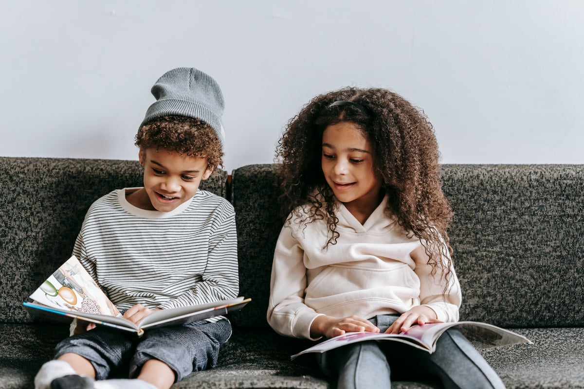 Happy adorable black children speaking while reading books